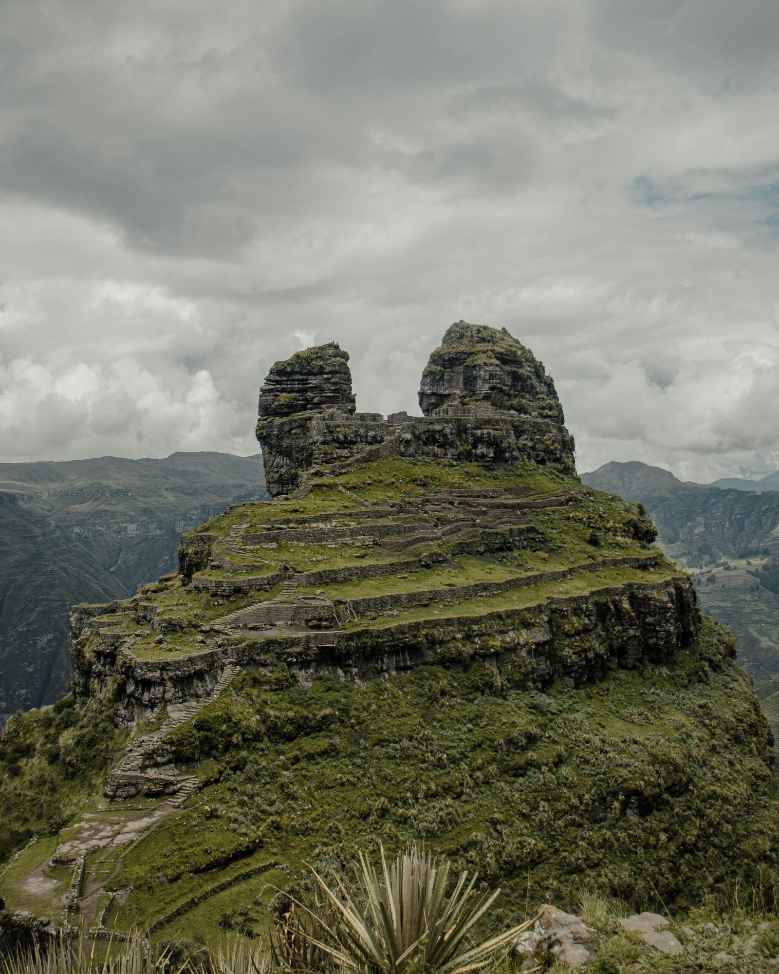 Explore Waqrapukara, ancient ruins amidst the stunning Andes mountains in Peru.
