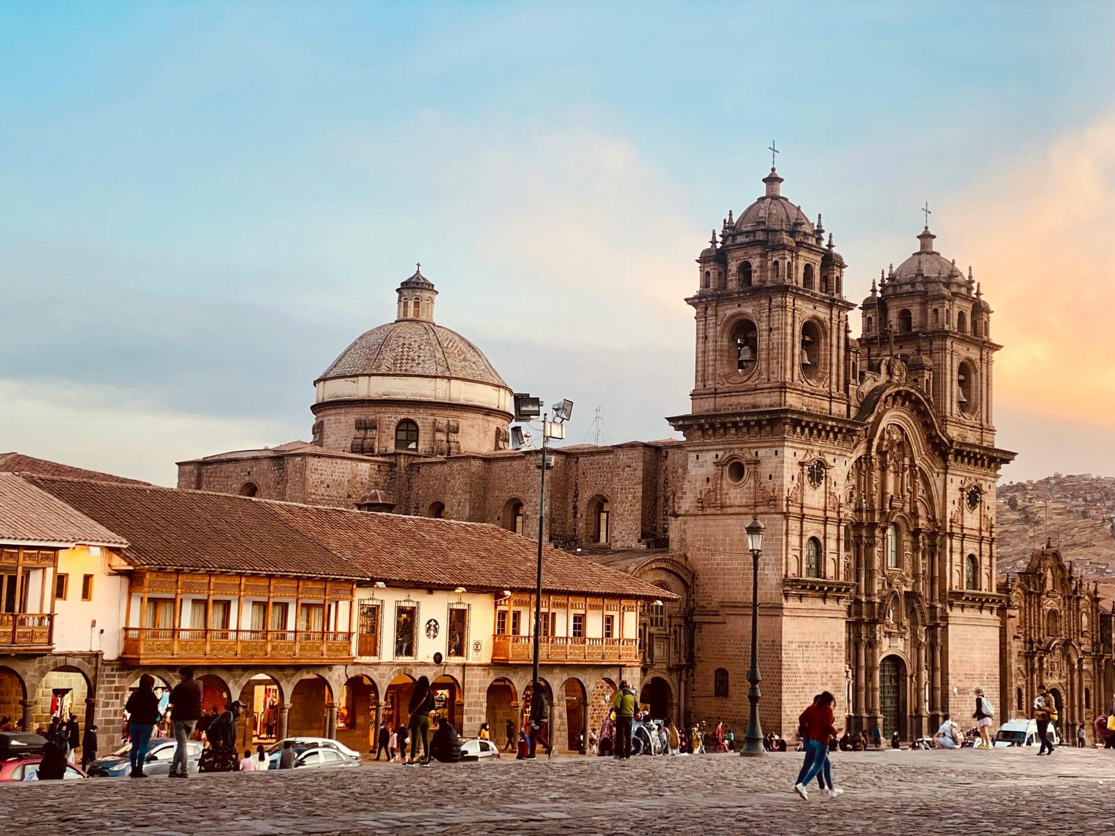 Scenic view of a historic church in Cusco, Peru with people walking at sunset.