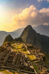 Breathtaking aerial view of Machu Picchu at sunset, showcasing Inca architecture and mountainous landscape.