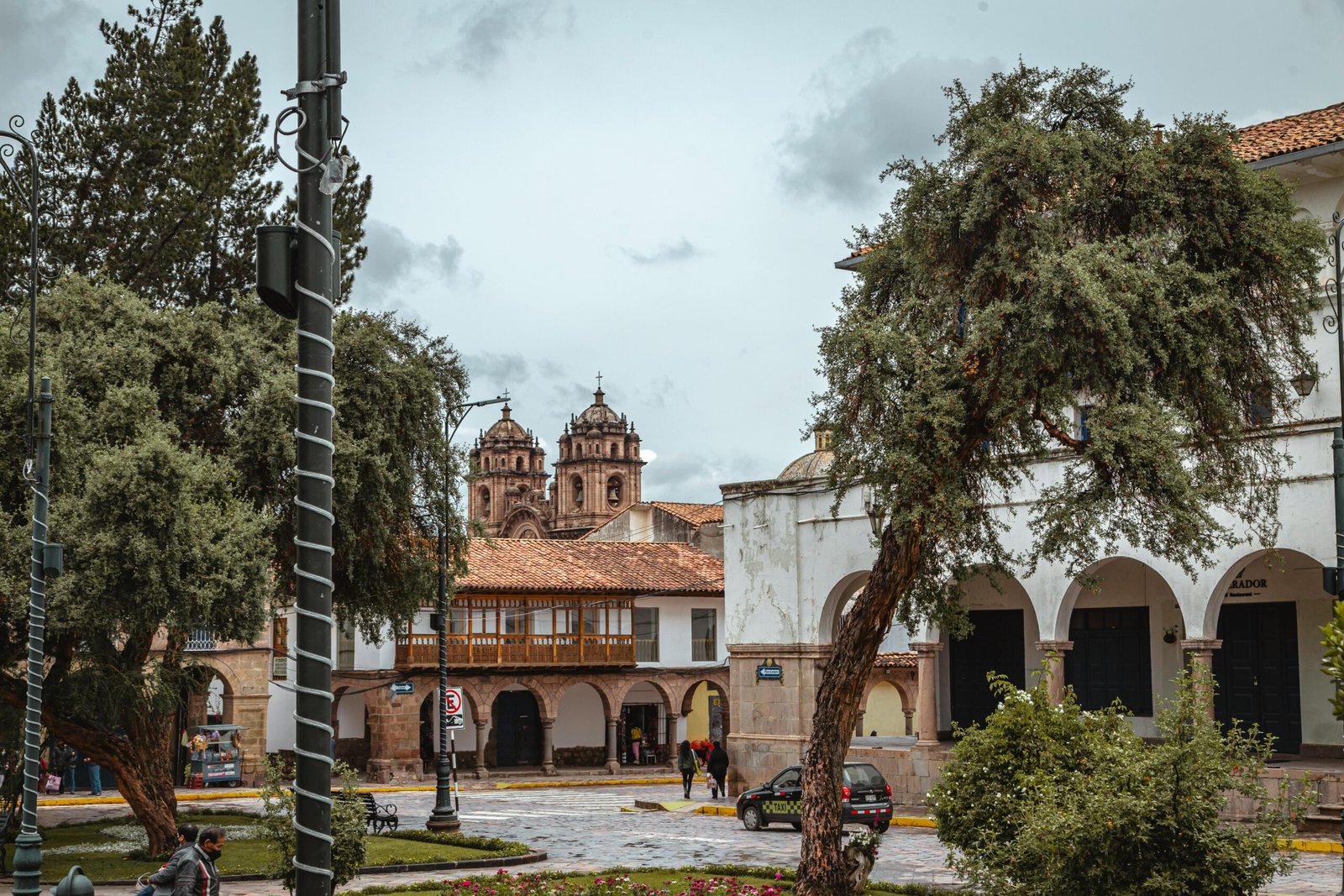 Charming view of a historical square in Cusco, Peru with colonial architecture and lush greenery.