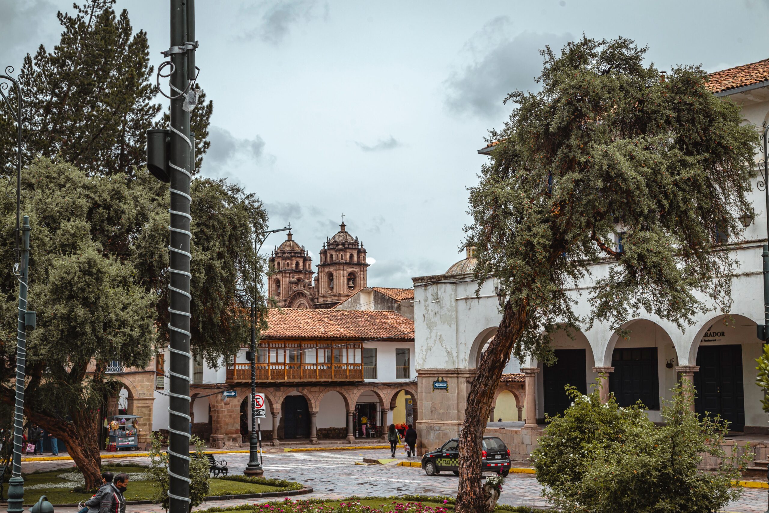 Charming view of a historical square in Cusco, Peru with colonial architecture and lush greenery.